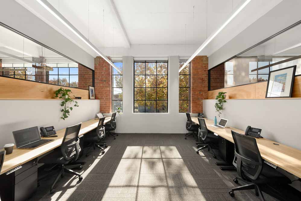 modern office space with heritage window and red brick desks along the walls and a l,ot of natural light