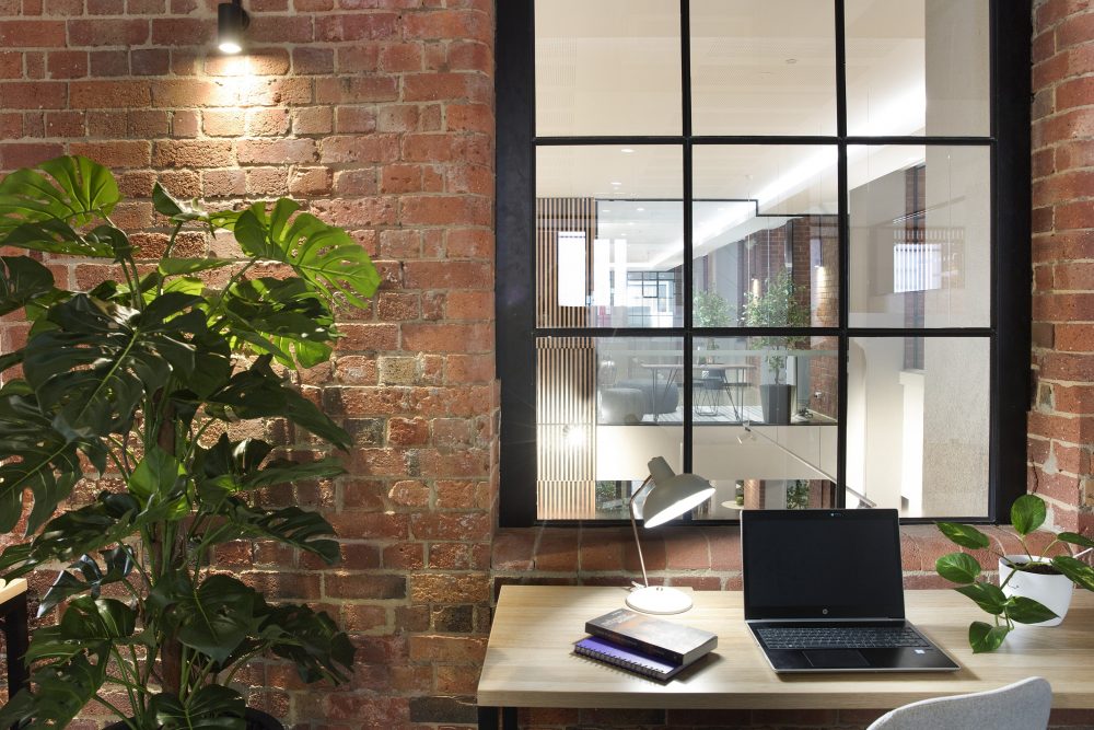 hot desk with lap top against a red brick wall with plants