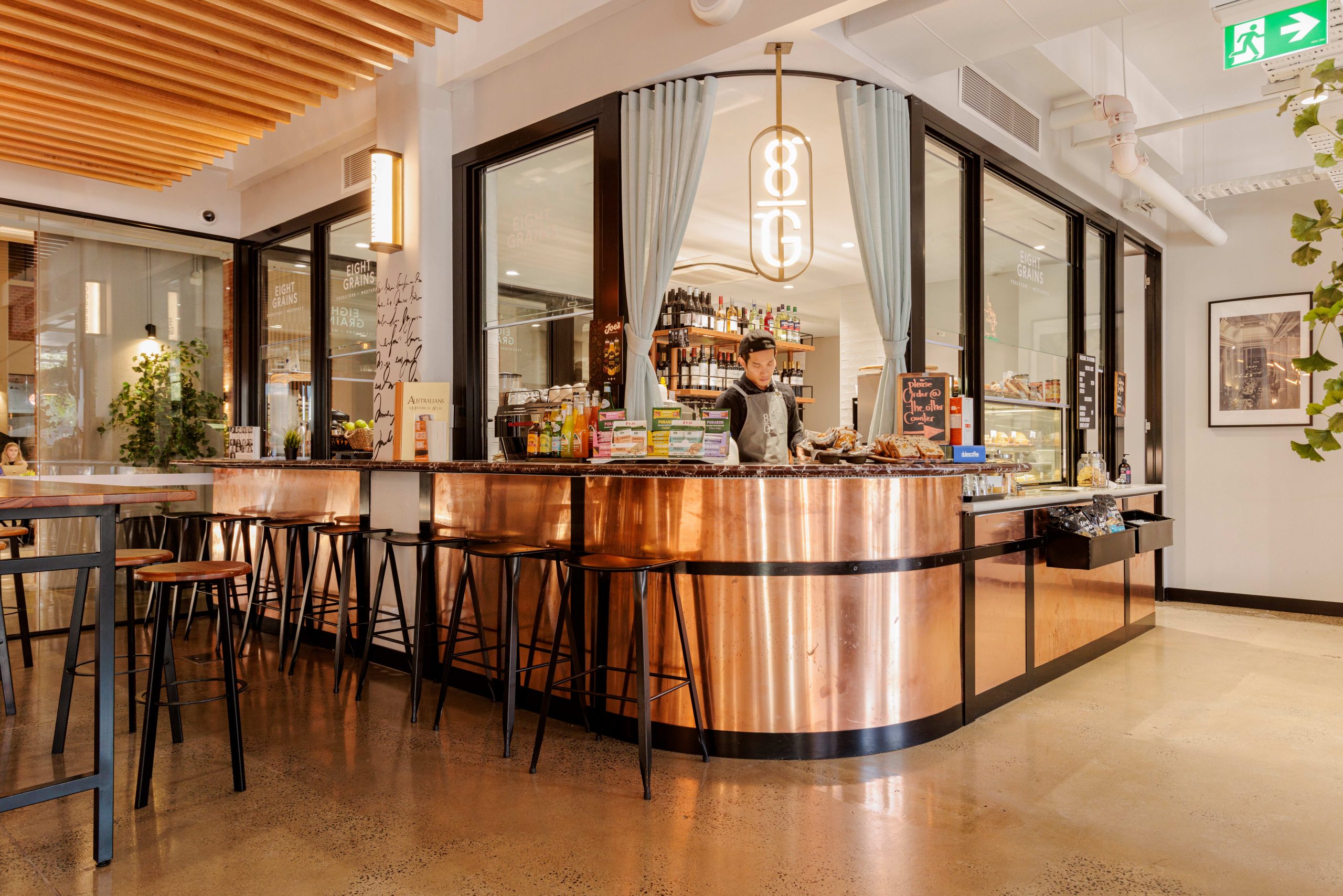 coppe cladded bar and cafe counter with barista making coffee