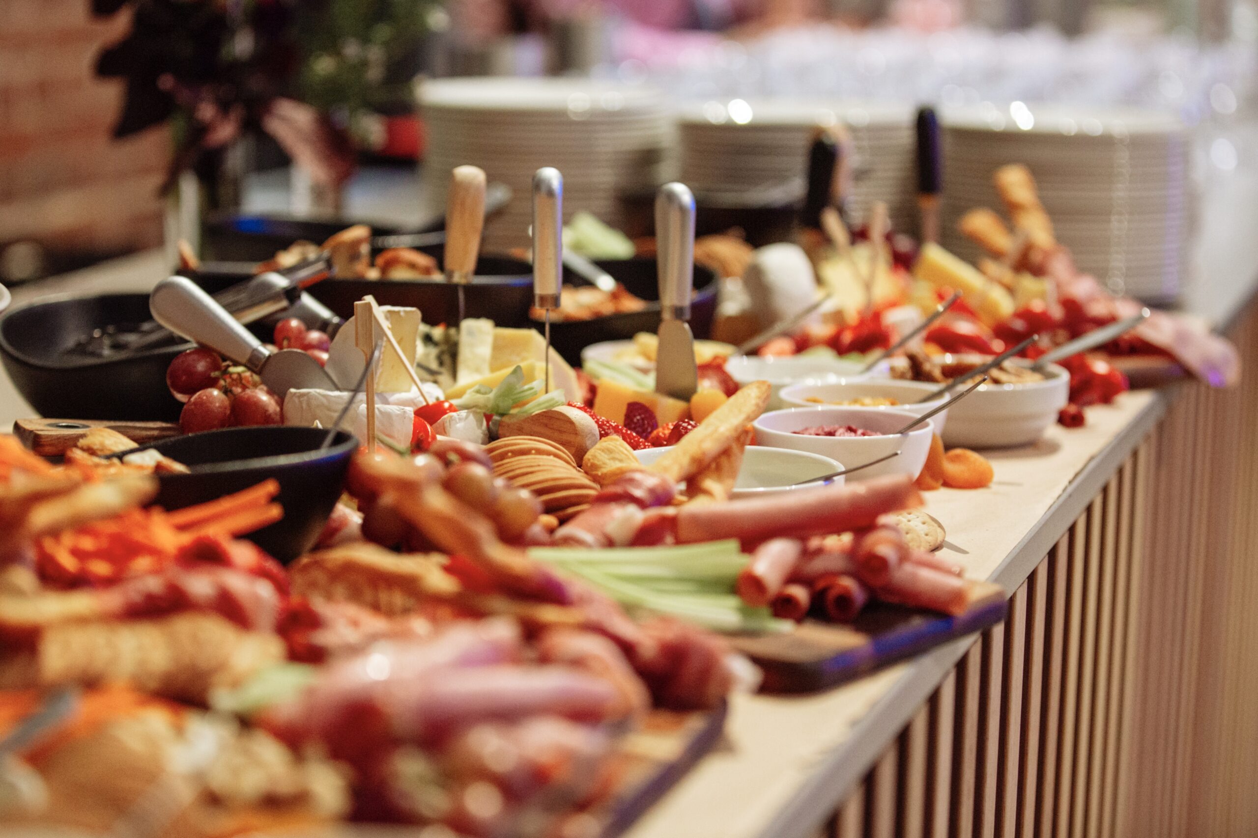 A table full of cheeses and cold meats with fresh fruits crackers and bread