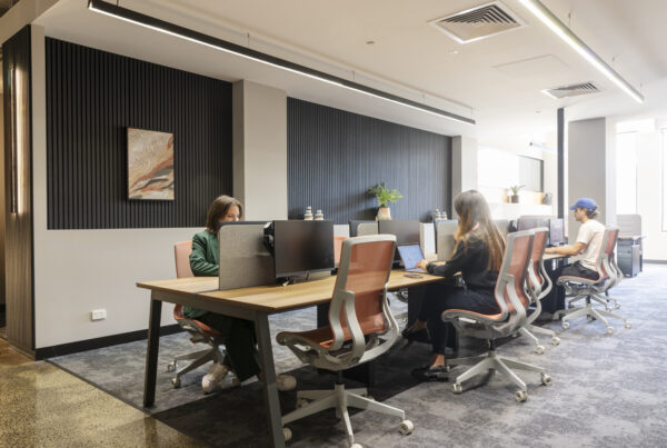 A coworking space with desks and monitors filled with natural light. multiple people working independently and collaboratively.