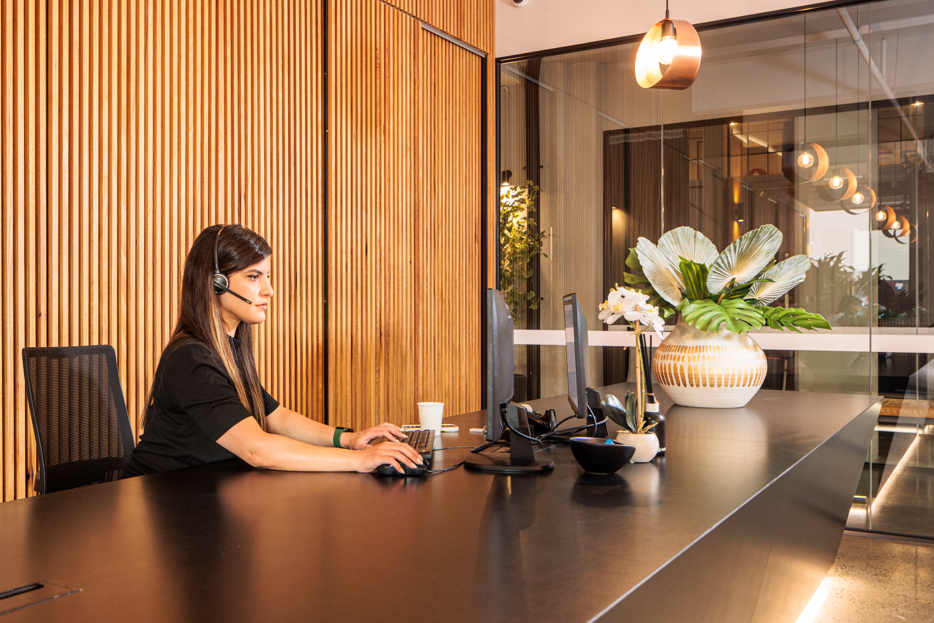 United Co. in Fitzroy Reception Area, a person sitting in front of their computer with headphones on and is working on their computer